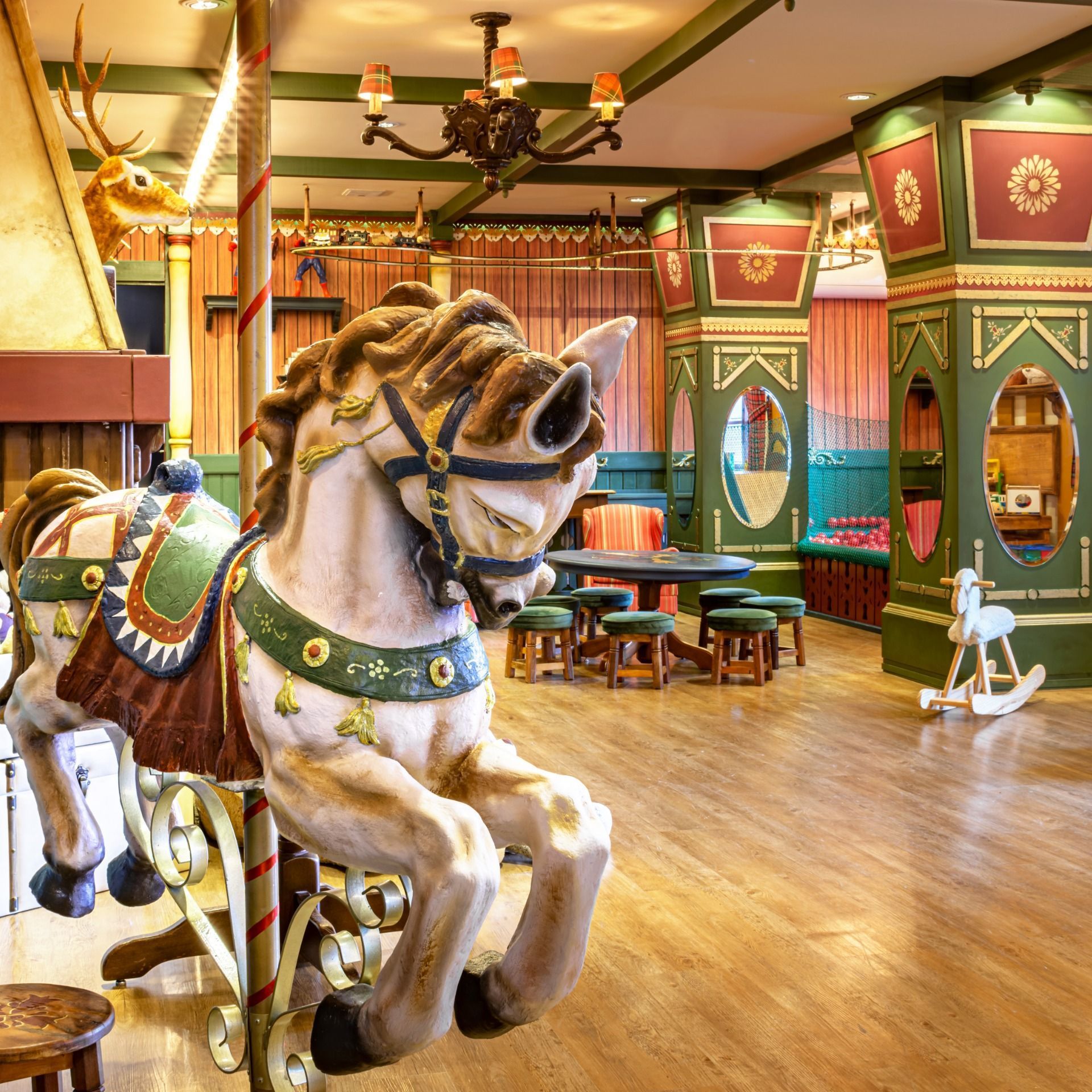 Cavalo de carrossel em um colorido espaço de diversões interno com piso de madeira e decoração ornamentada.