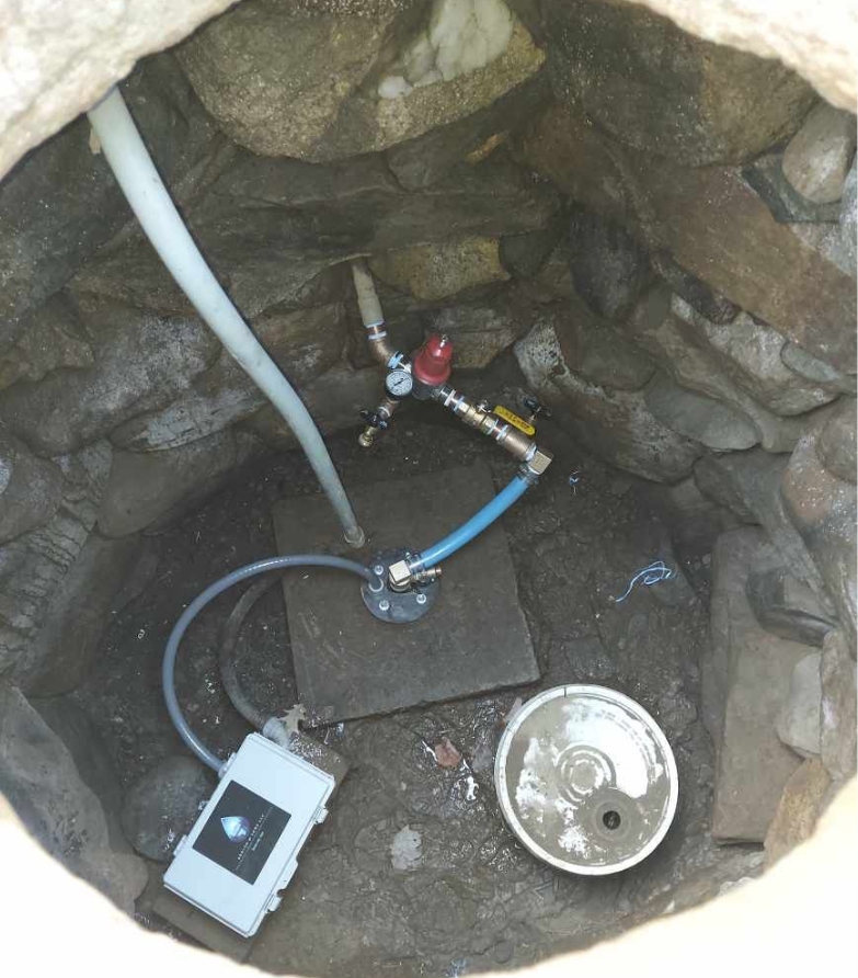 Well pit with water pump components and electronic device.
