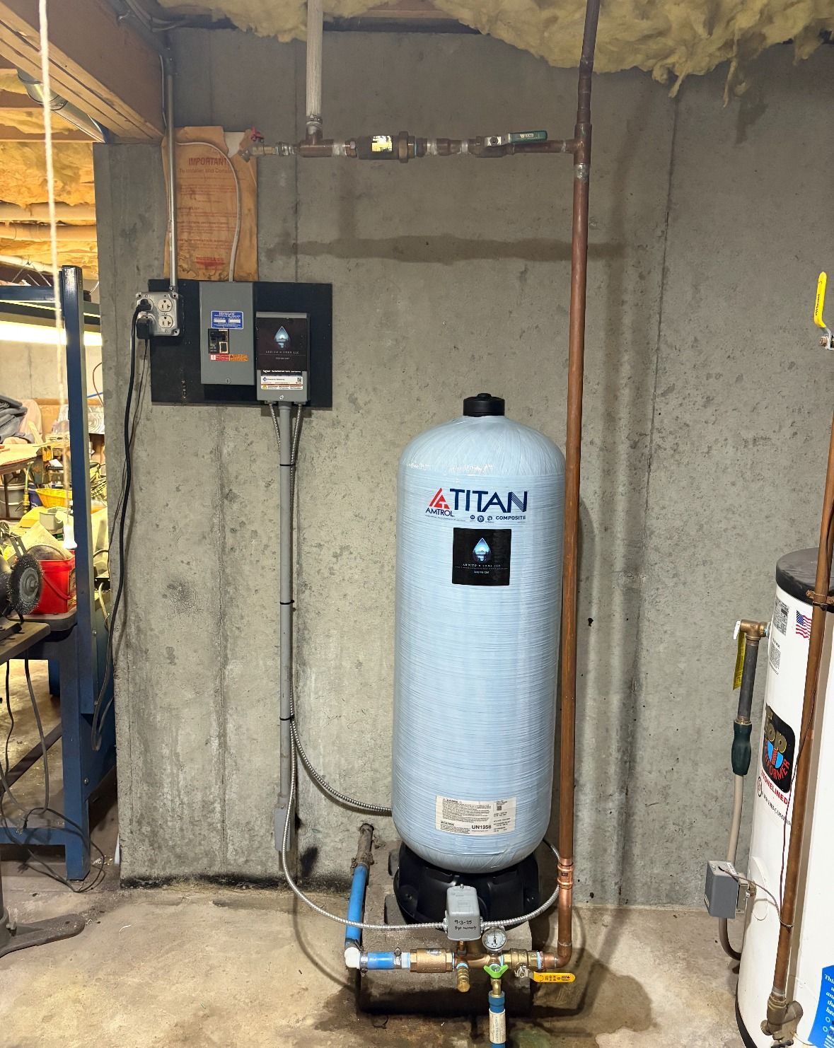 Well pressure tank system in a basement with control panel and copper pipes.