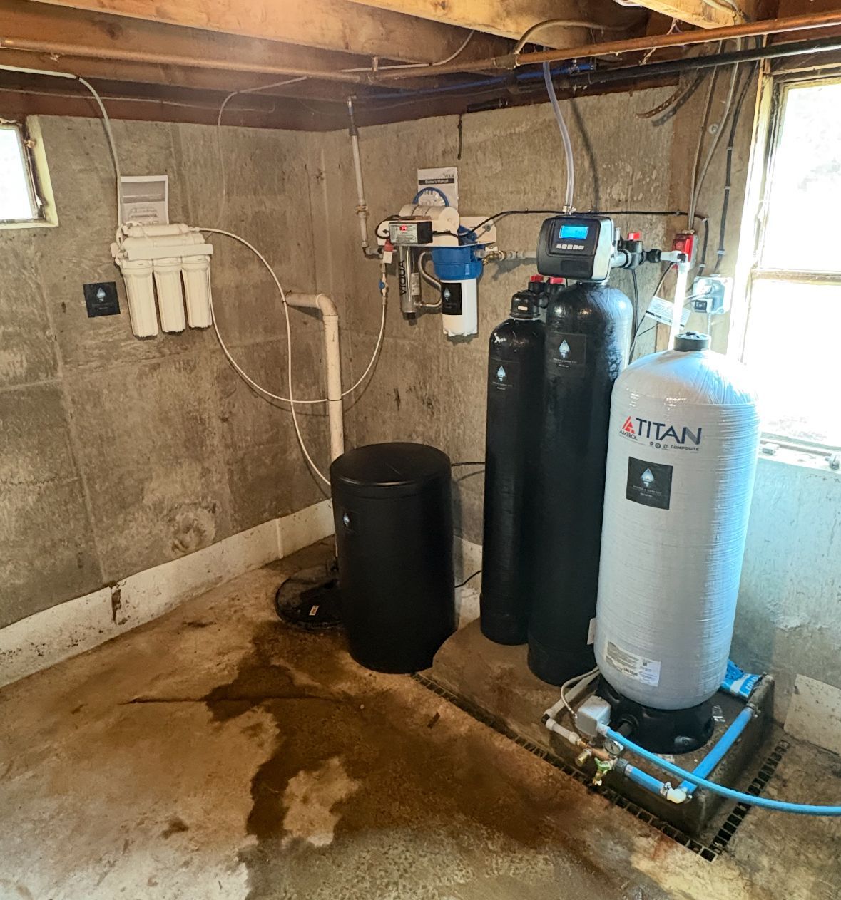 Water filtration and treatment system in a basement setting; includes tanks, filters, and pipes.