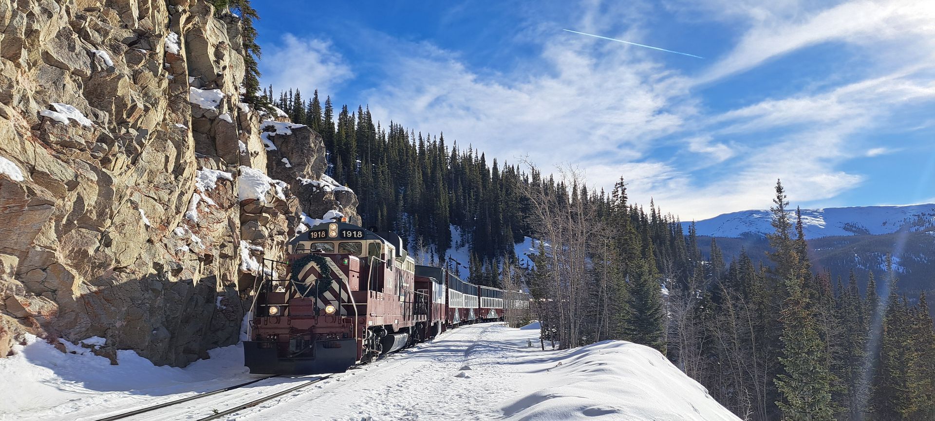 A train is going down the tracks in the snow.