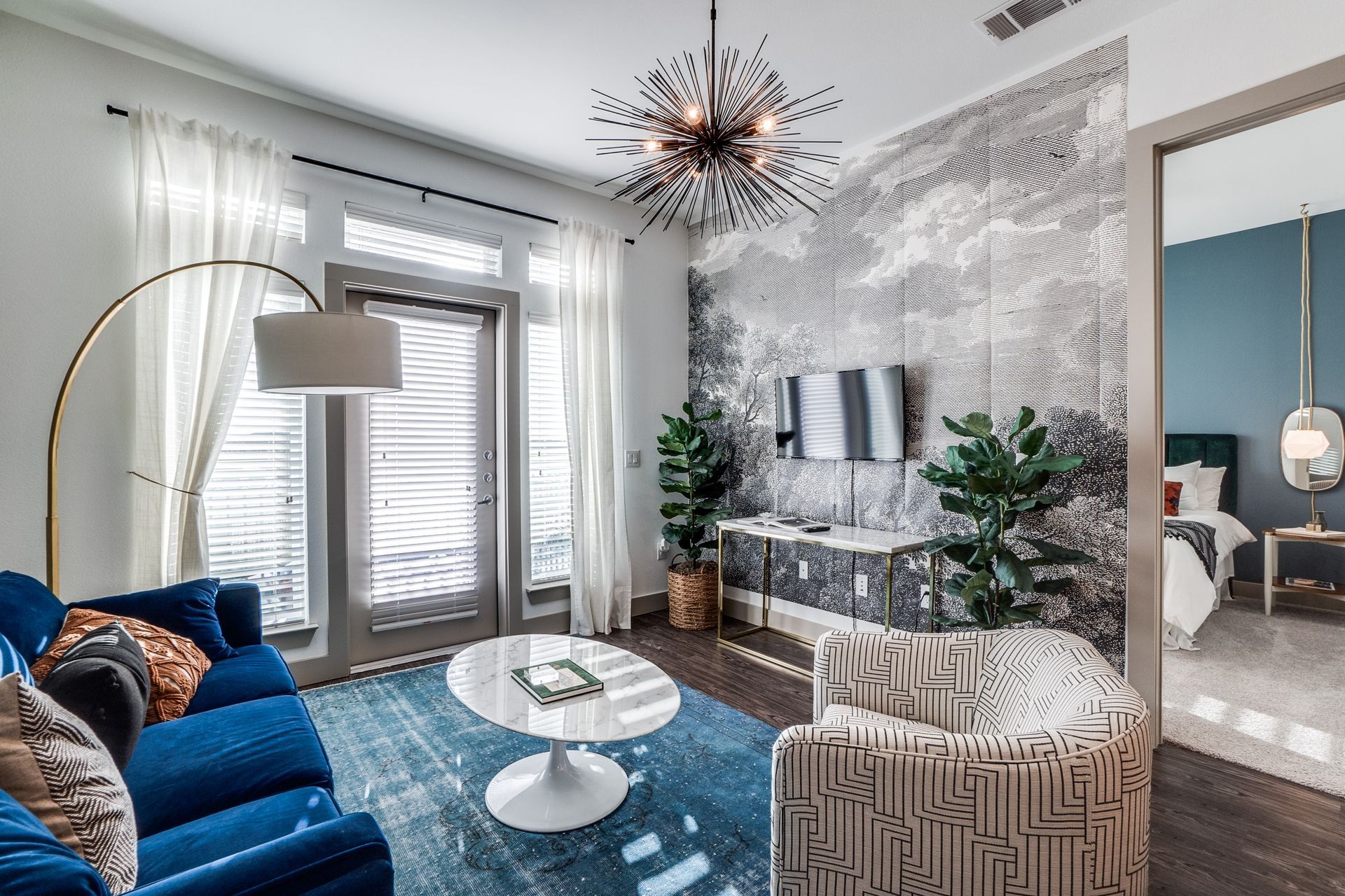 A living room with a blue couch , chair , coffee table and television.