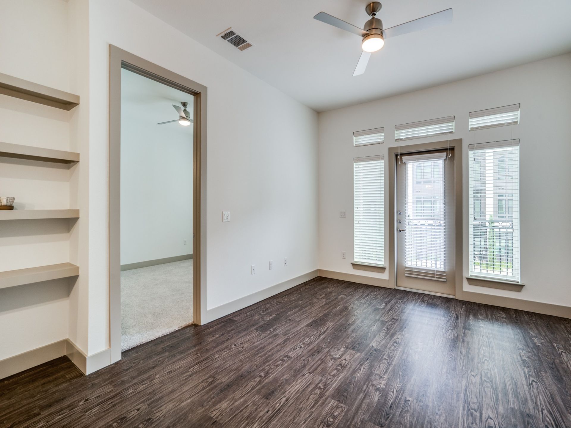 An empty living room with hardwood floors and a ceiling fan.