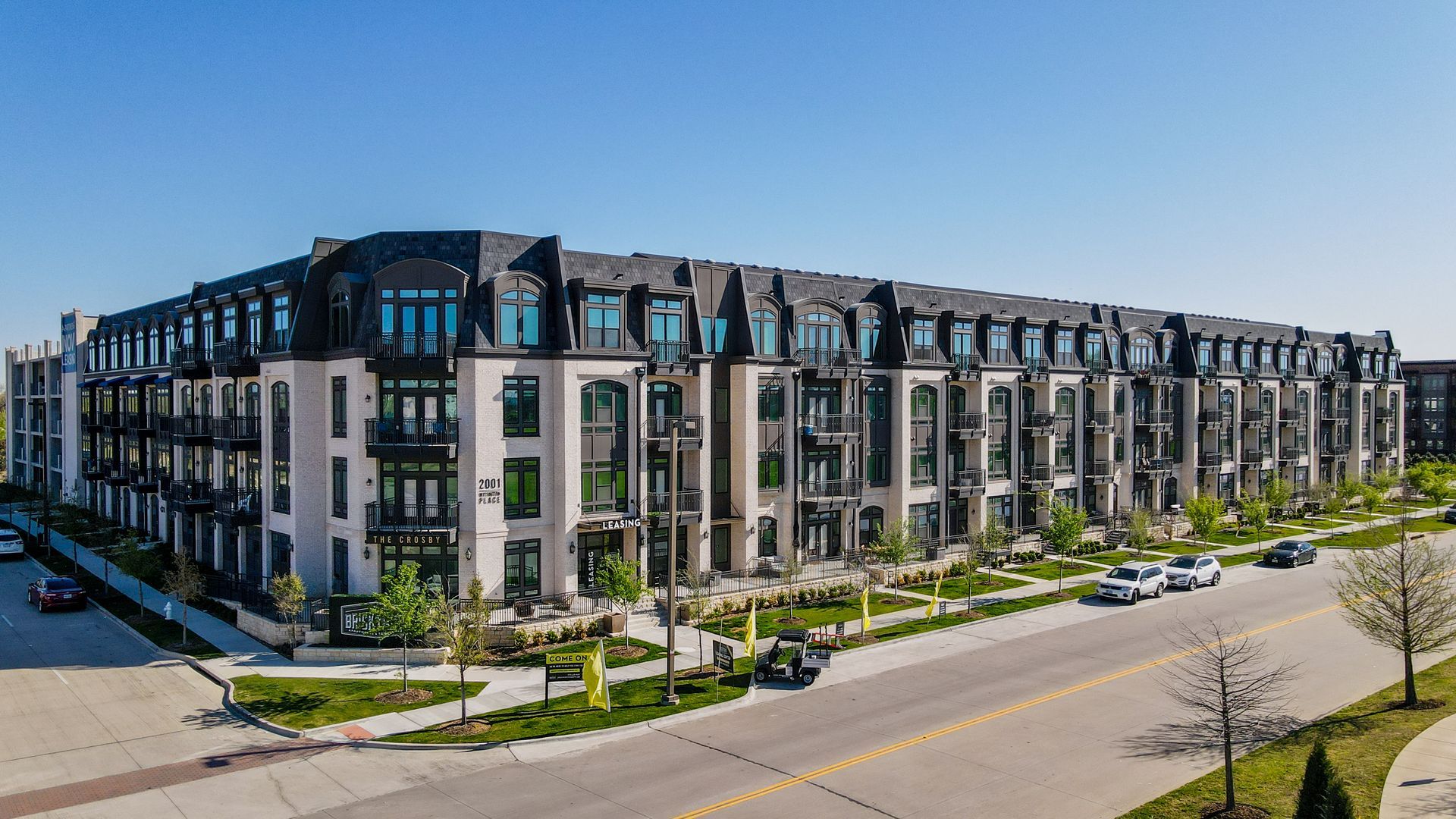 An aerial view of a large apartment building next to a street.