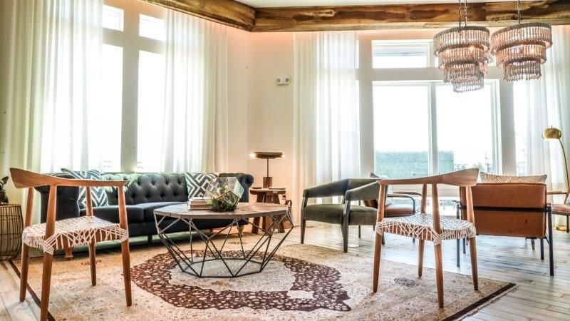 A living room with a couch , chairs , a table and a rug.