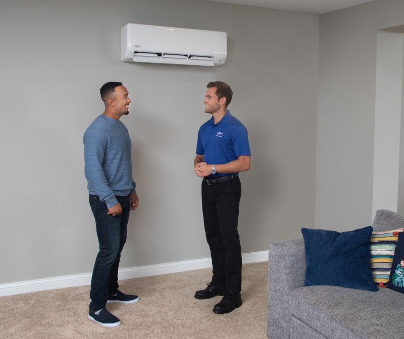 Two men are standing in a living room talking to each other.