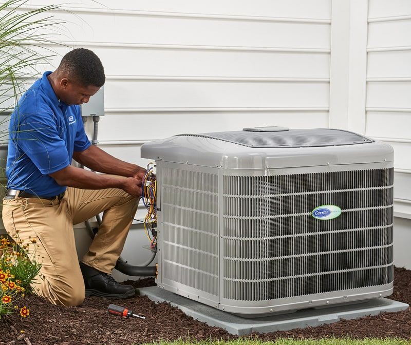 A man is working on an air conditioner outside of a house.