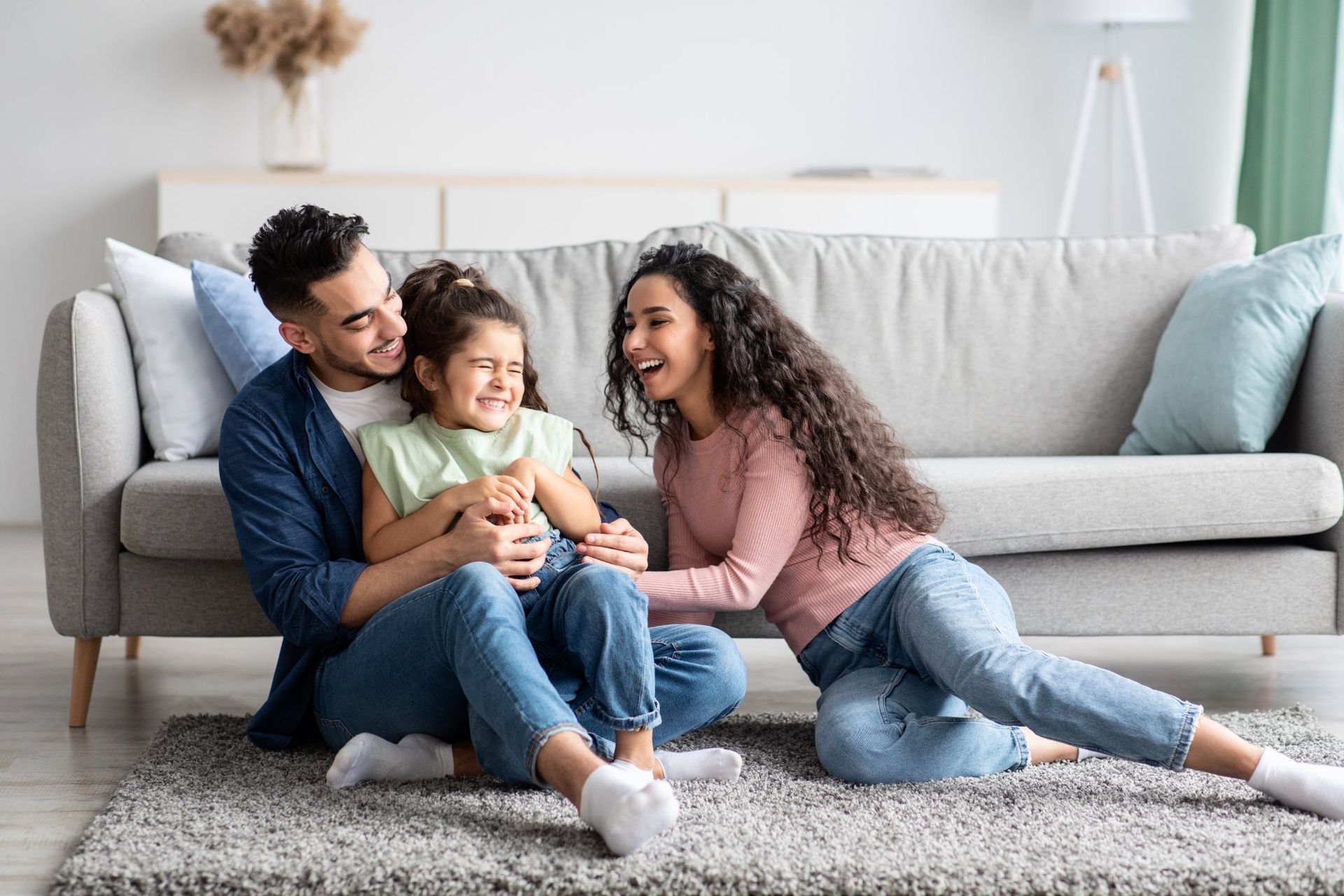 A family is sitting on the floor in front of a couch.