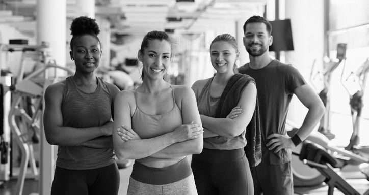 Multiracial team of young athletes with crossed arms in a gym looking at camera