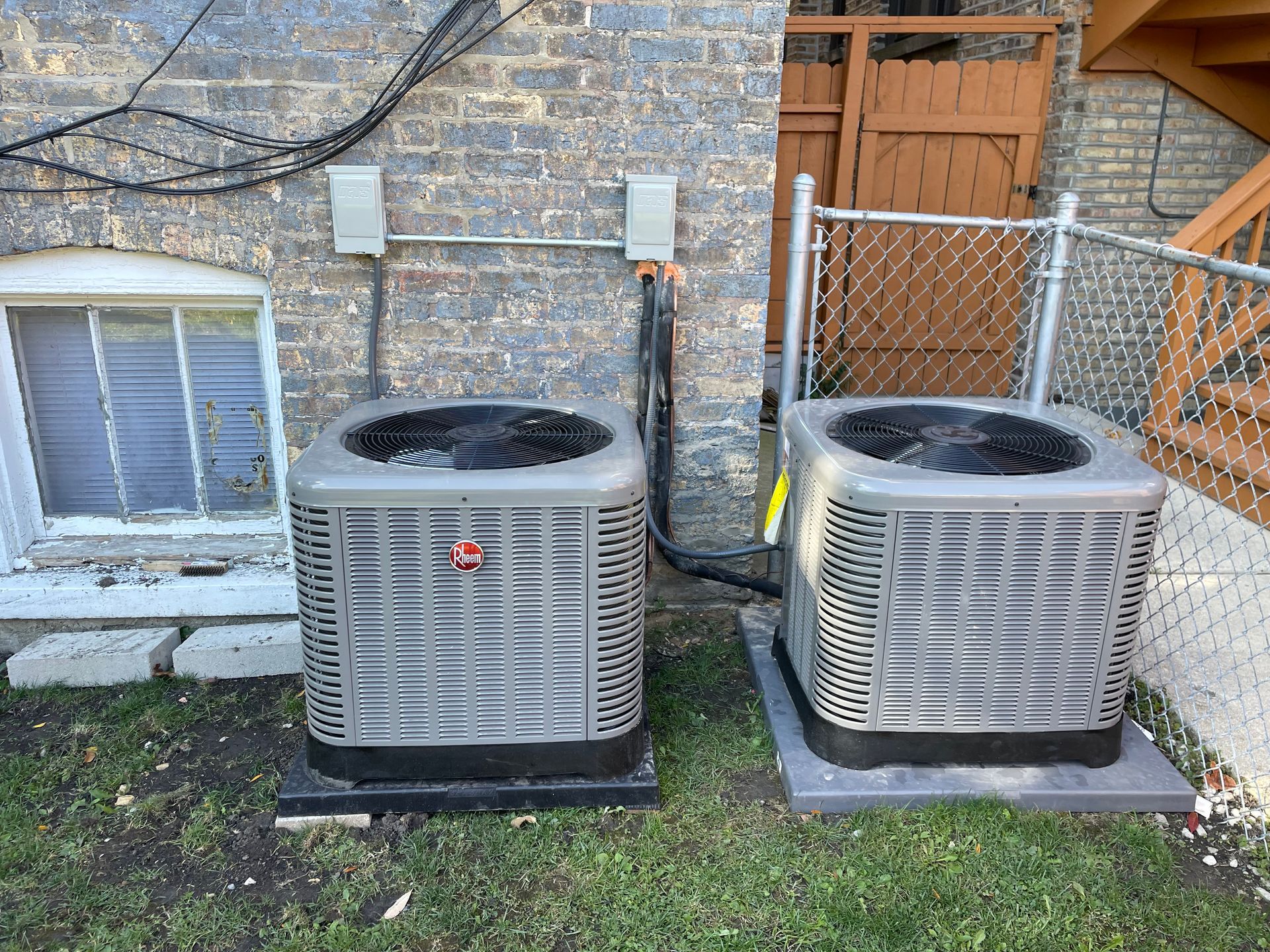 Dual Rheem HVAC units outside a brick home for efficient air conditioning service