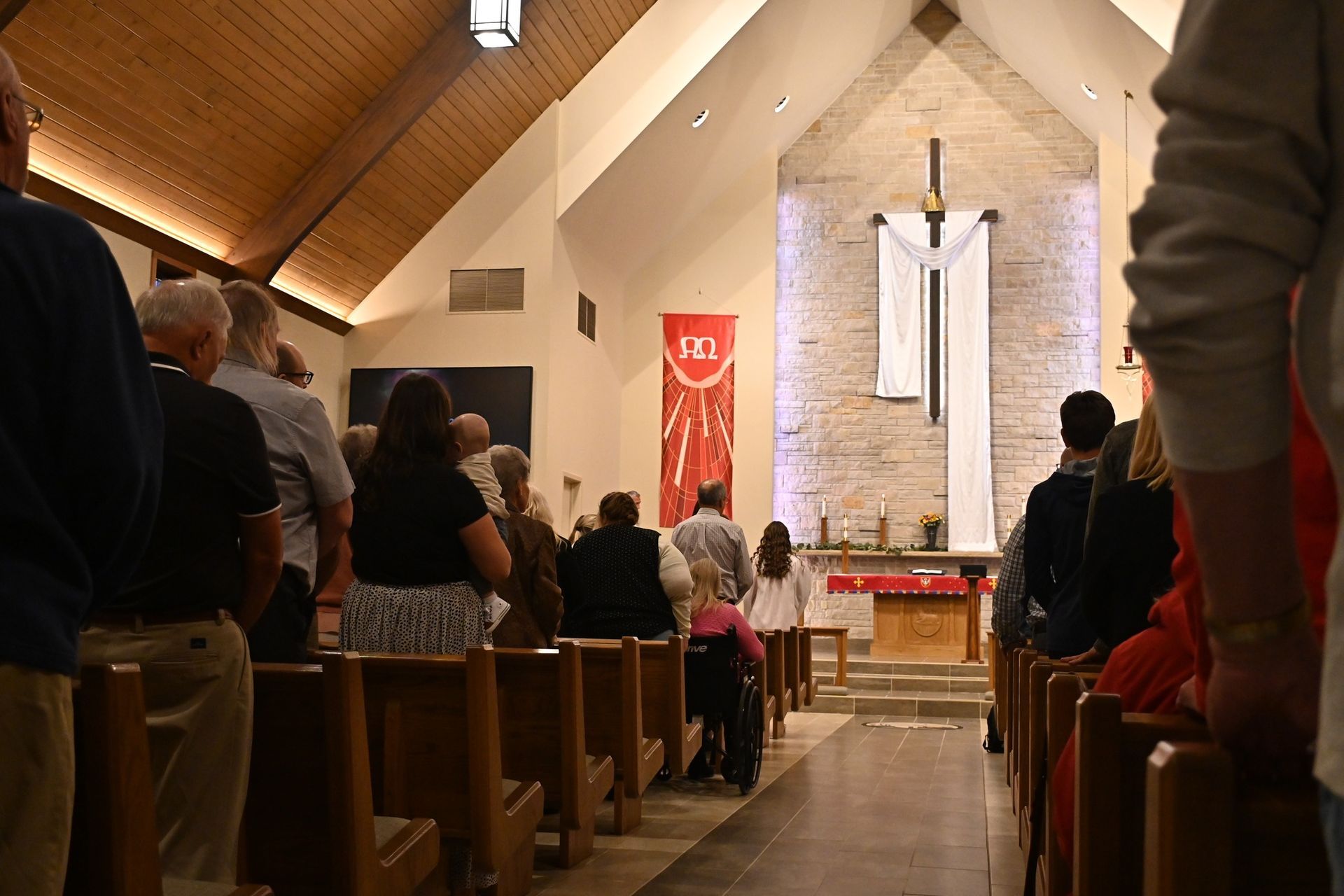 People seated in a church pews facing the altar during a service.
