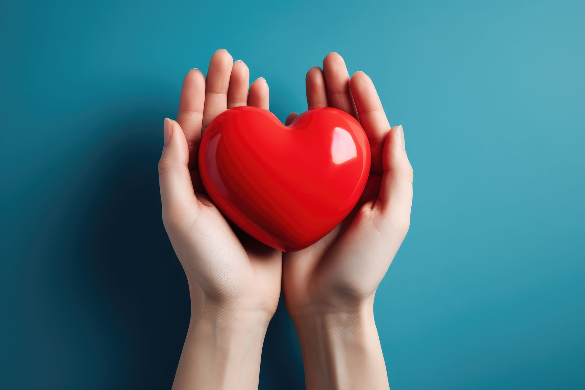 Zwei Hände halten vorsichtig ein glänzendes rotes Herz vor einem blauen Hintergrund, symbolisch für Liebe und Fürsorge.