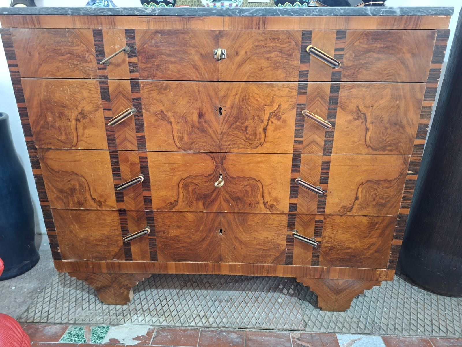 Cassettiera antica in legno a quattro cassetti con impiallacciatura in noce radica a venatura simmetrica, intarsi verticali a strisce e piano in marmo.