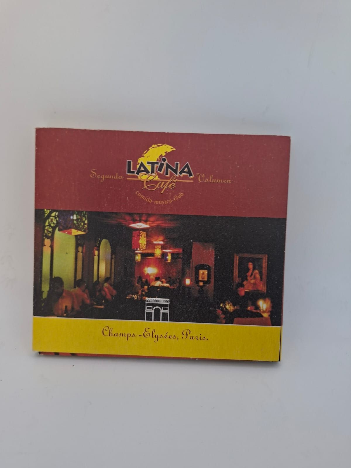 Un biglietto promozionale quadrato per un ristorante latinoamericano, con una scena di interni di una sala da pranzo, il logo del ristorante e l'indicazione della località di Parigi.