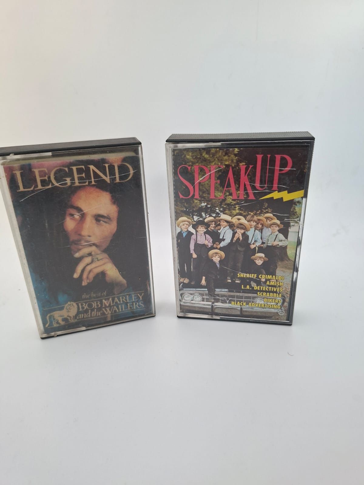 Due cassette audio posizionate verticalmente su una superficie bianca: 