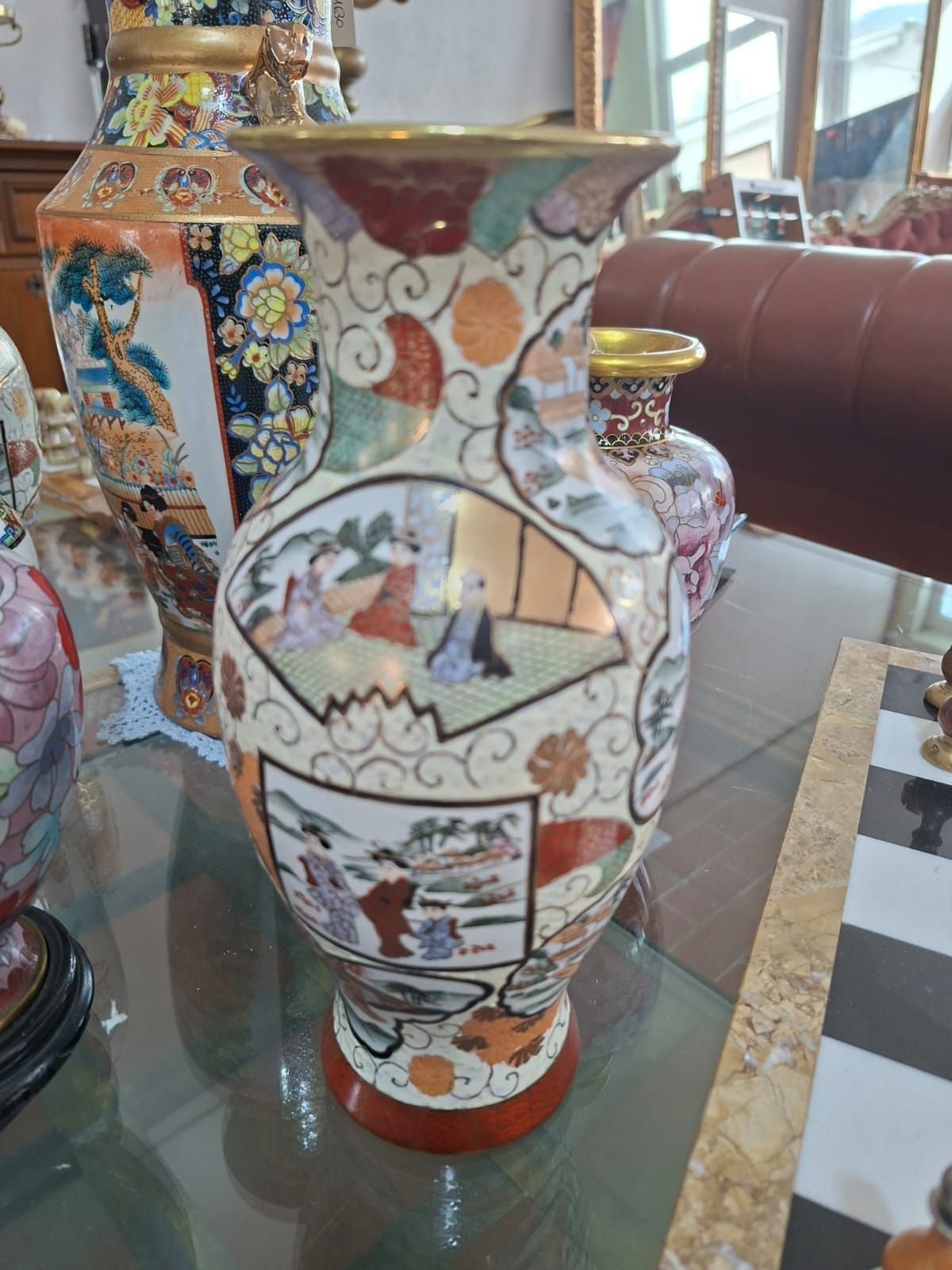 Un vaso decorativo in ceramica multicolore con dipinti in stile giapponese raffiguranti figure su un tavolo.