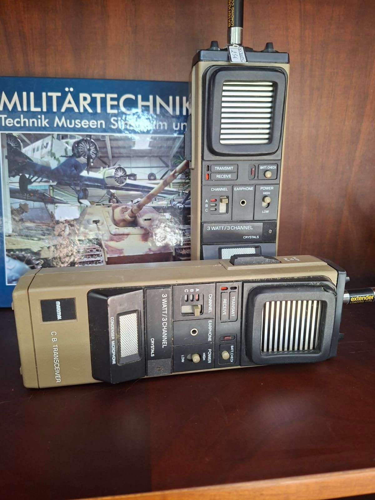 Due walkie-talkie vintage di colore beige sono posizionati su una superficie di legno scuro davanti a un libro intitolato 