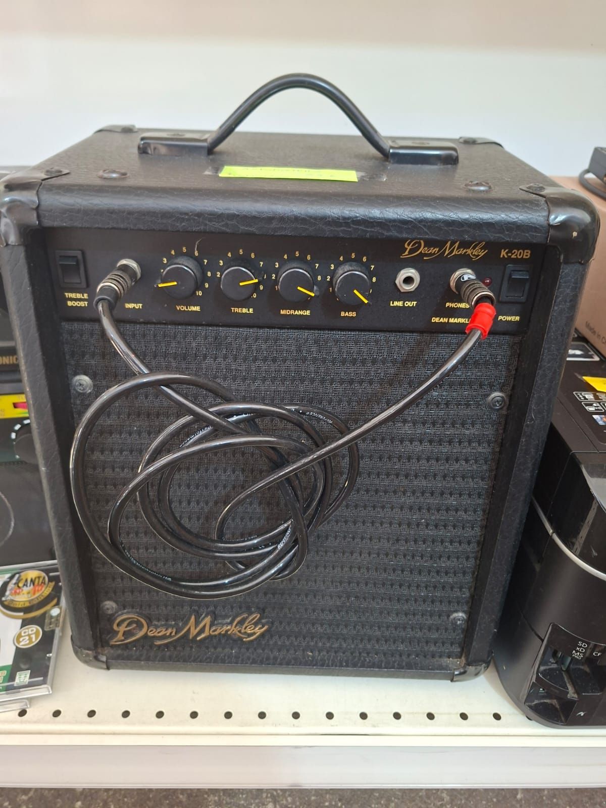 Un amplificatore per basso Dean Markley K-20B nero con un cavo a spirale collegato all'ingresso e al jack per le cuffie.