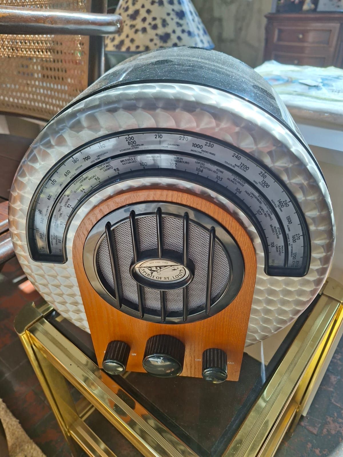 Una radio da tavolo rotonda in stile vintage con centro effetto legno, griglia dell'altoparlante nera e quadrante color argento.