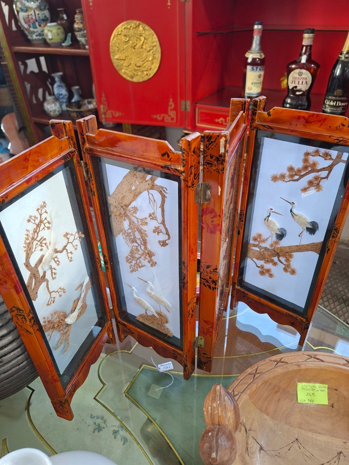 Un paravento da tavolo a quattro pannelli con cornice in legno, decorato con intarsi in conchiglia raffiguranti gru e pini.