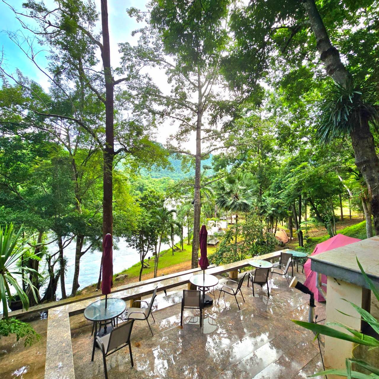 A patio with tables and chairs overlooking a river