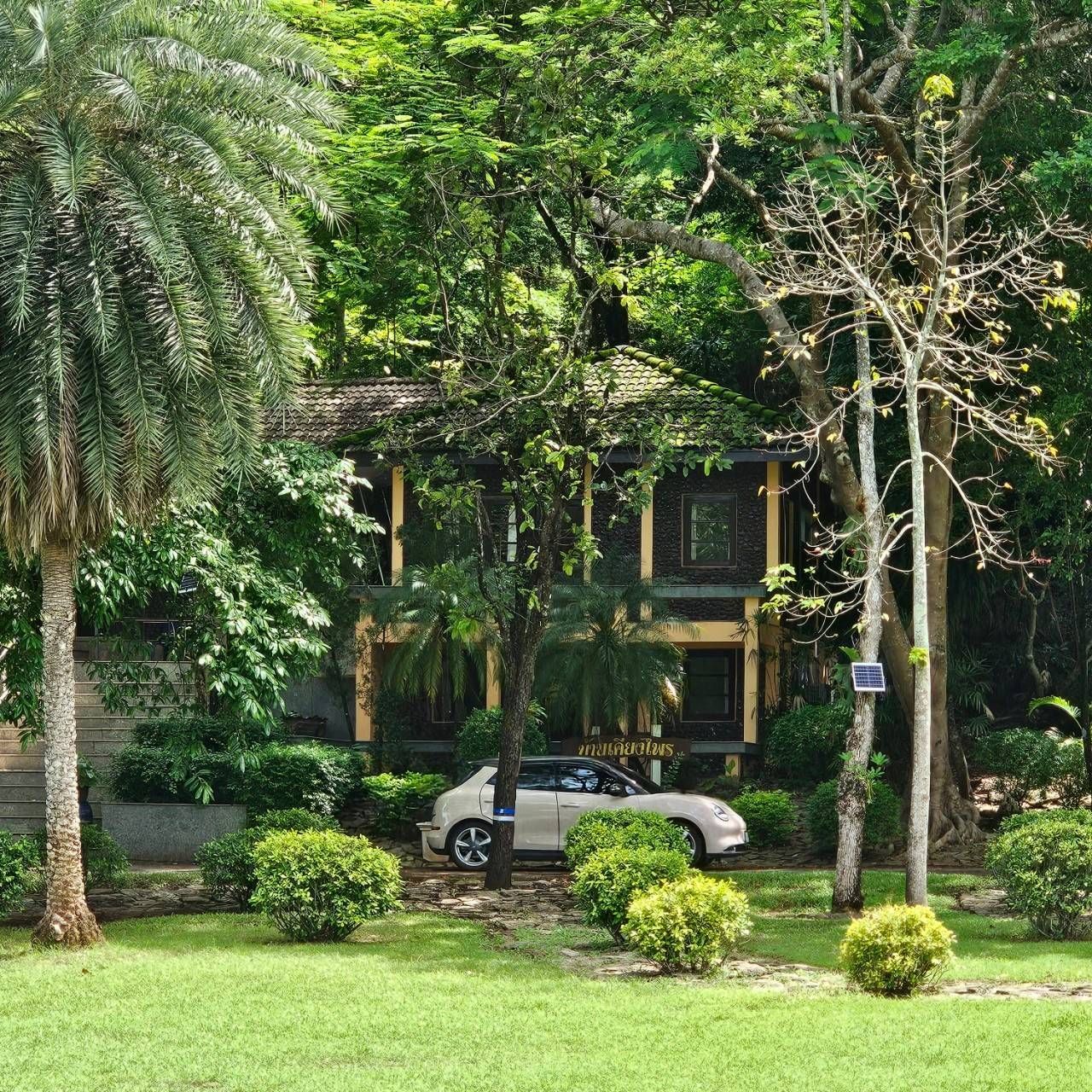 A white car is parked in front of a house surrounded by trees