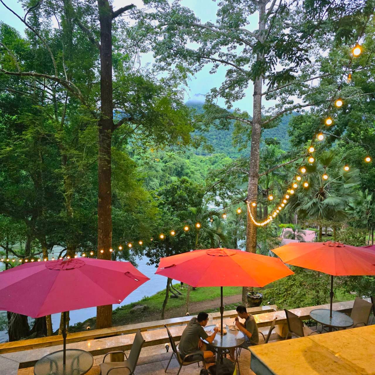 A couple sits at a table under a pink umbrella