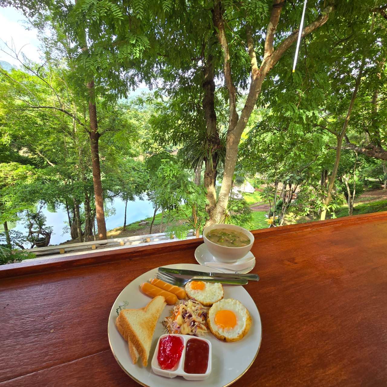 A plate of food on a wooden table with trees in the background