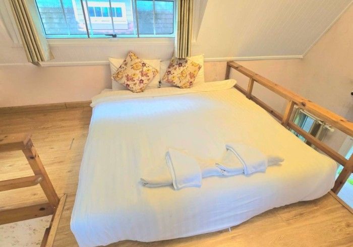 A bed is sitting on top of a wooden floor next to a window.