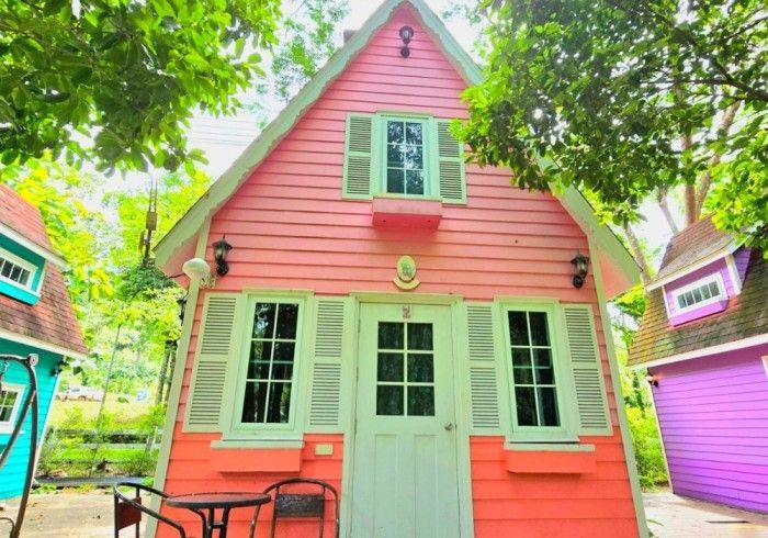 A pink house with white shutters and a table and chairs in front of it.