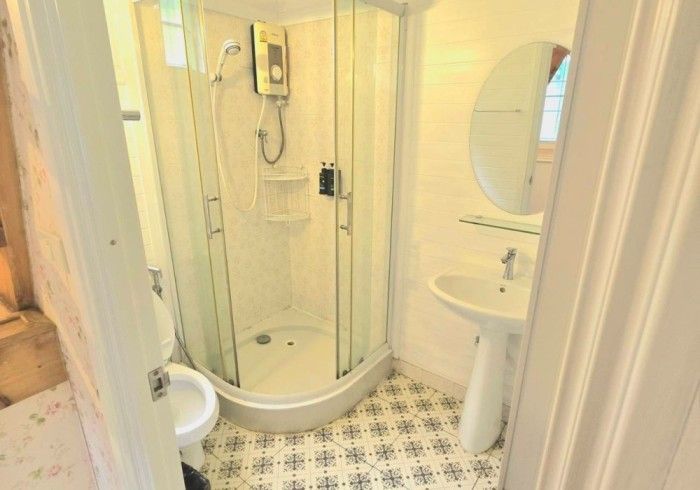 A bathroom with a shower , sink , toilet and mirror.