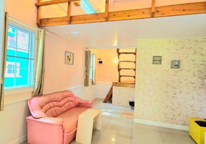 A living room with a pink couch and a yellow chair