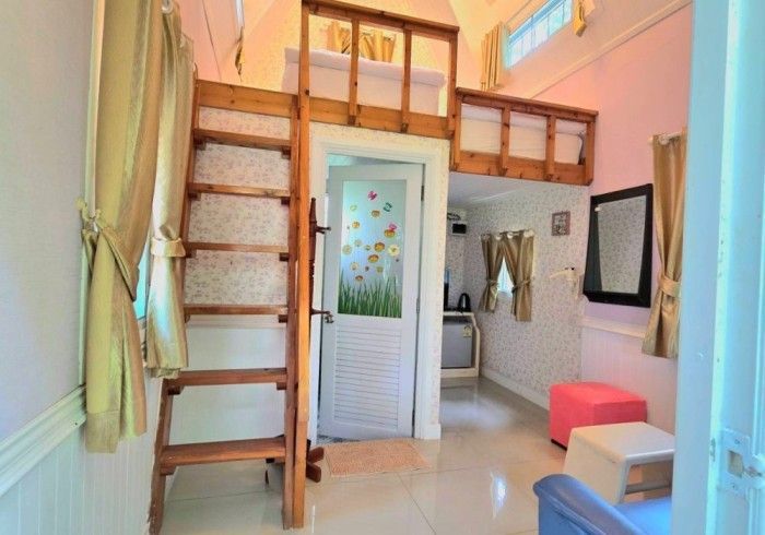 A living room with a staircase leading up to a loft bed.