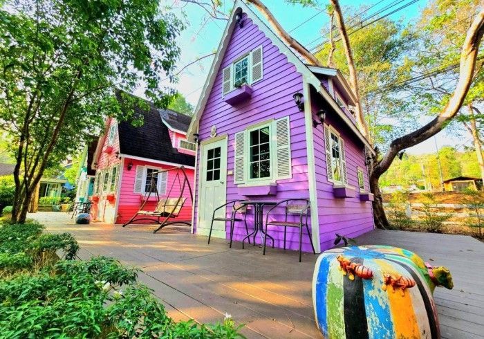 A purple and pink house with a table and chairs in front of it.
