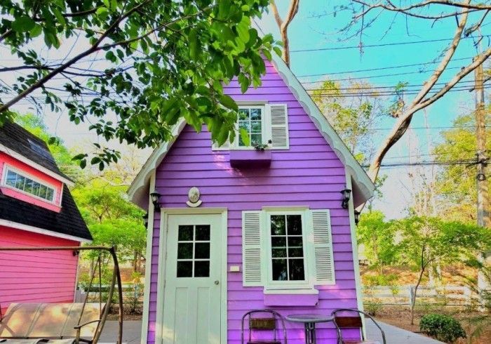 A purple house with white shutters and a pink house in the background.