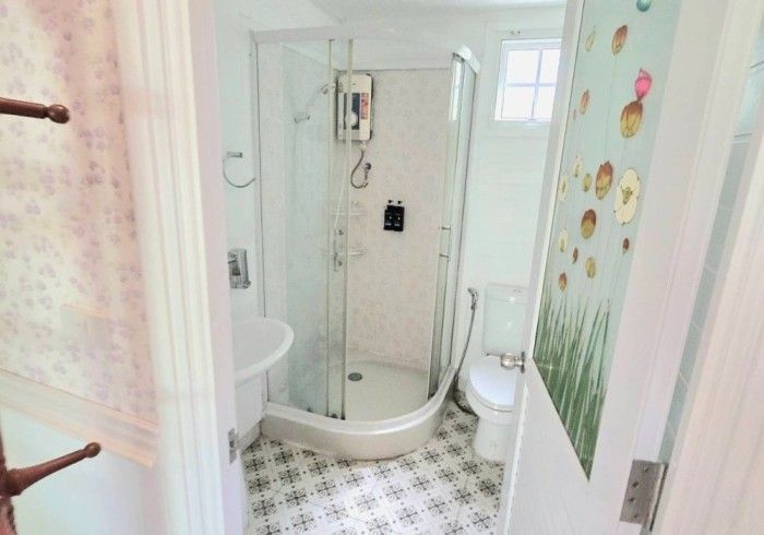 A bathroom with a shower , toilet , sink and mirror.