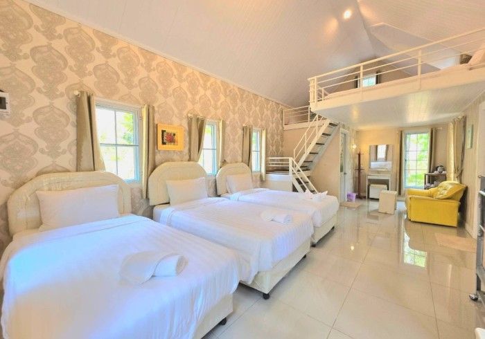 A hotel room with three beds and a yellow couch.