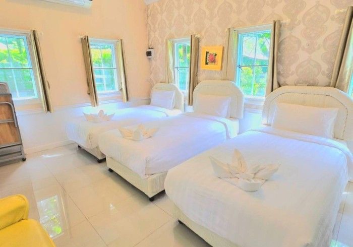 A hotel room with three beds and a yellow chair.