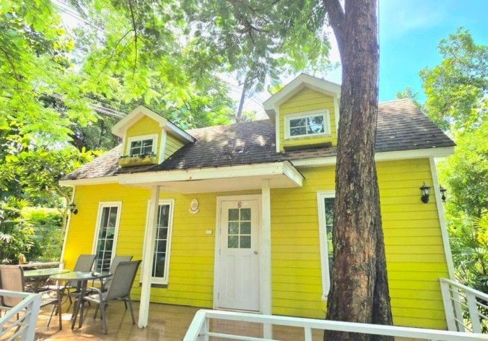 A yellow house with a tree in front of it