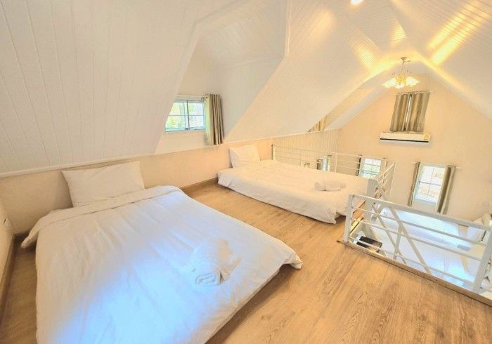 A bedroom with two beds and a staircase leading to the second floor.