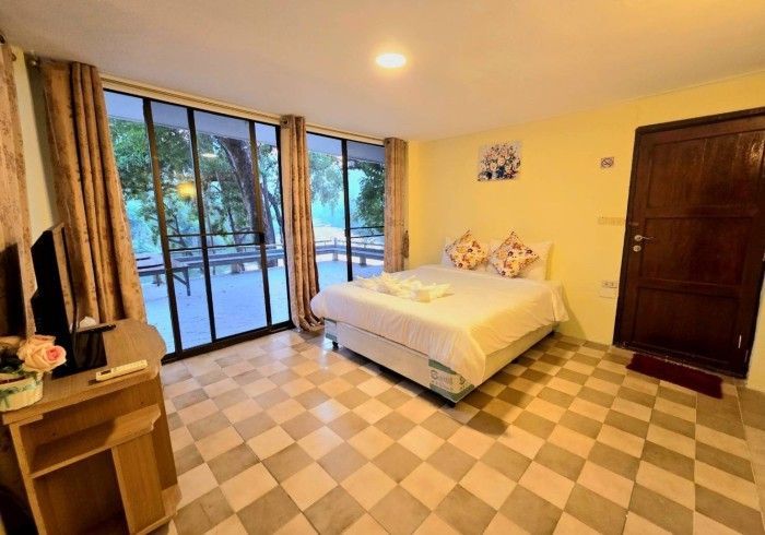 A hotel room with a bed , desk , television and sliding glass doors.