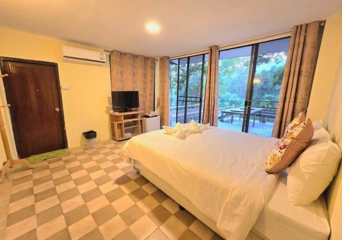 A hotel room with a king size bed , a television , and a balcony.