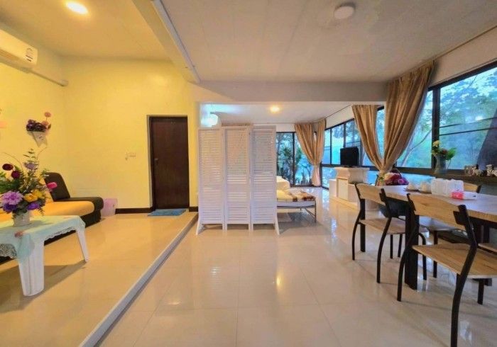 A living room with a dining table and chairs and a divider.