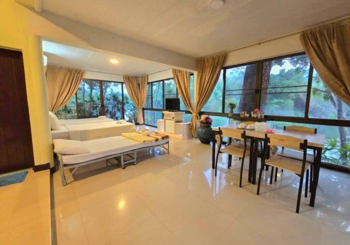 A living room with a dining table and chairs and a lot of windows.