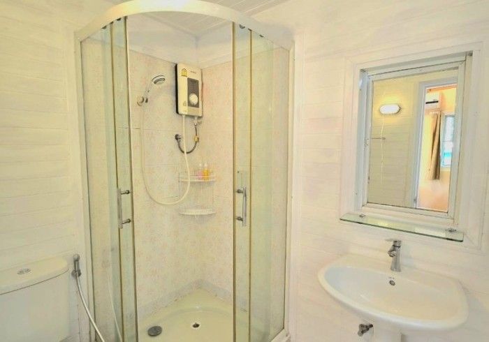 A bathroom with a shower , sink and mirror.