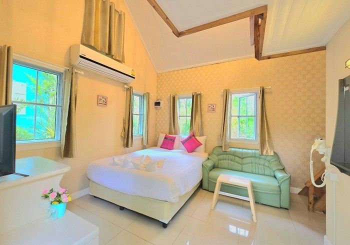 A hotel room with a bed , couch , television and air conditioner.