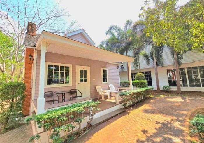 A small house with a porch and chairs in front of it.