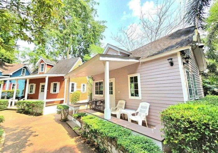 A small house with a porch and chairs in front of it.
