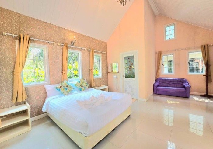 A bedroom with a king size bed and a purple couch.