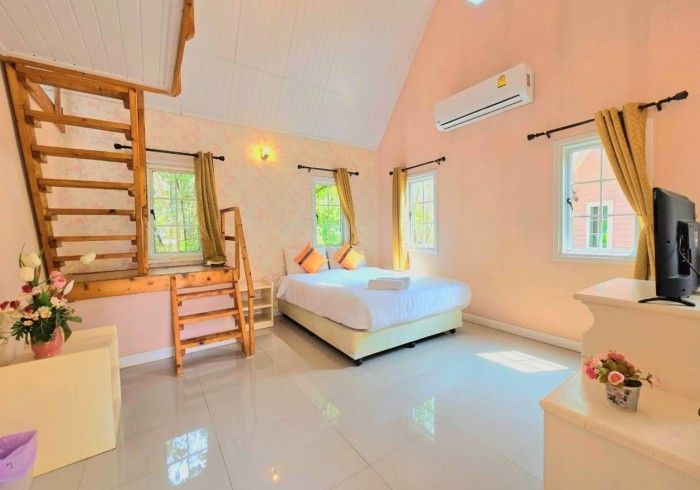 A bedroom with a bed , television , and stairs leading to the second floor.